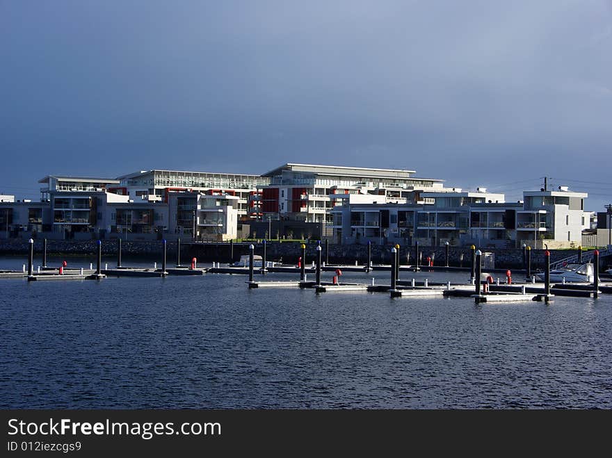Pontoons floating in the marina front of a block of modern eco style apartments, with a storm brewing overhead. Adelaide, South Australia. Pontoons floating in the marina front of a block of modern eco style apartments, with a storm brewing overhead. Adelaide, South Australia.