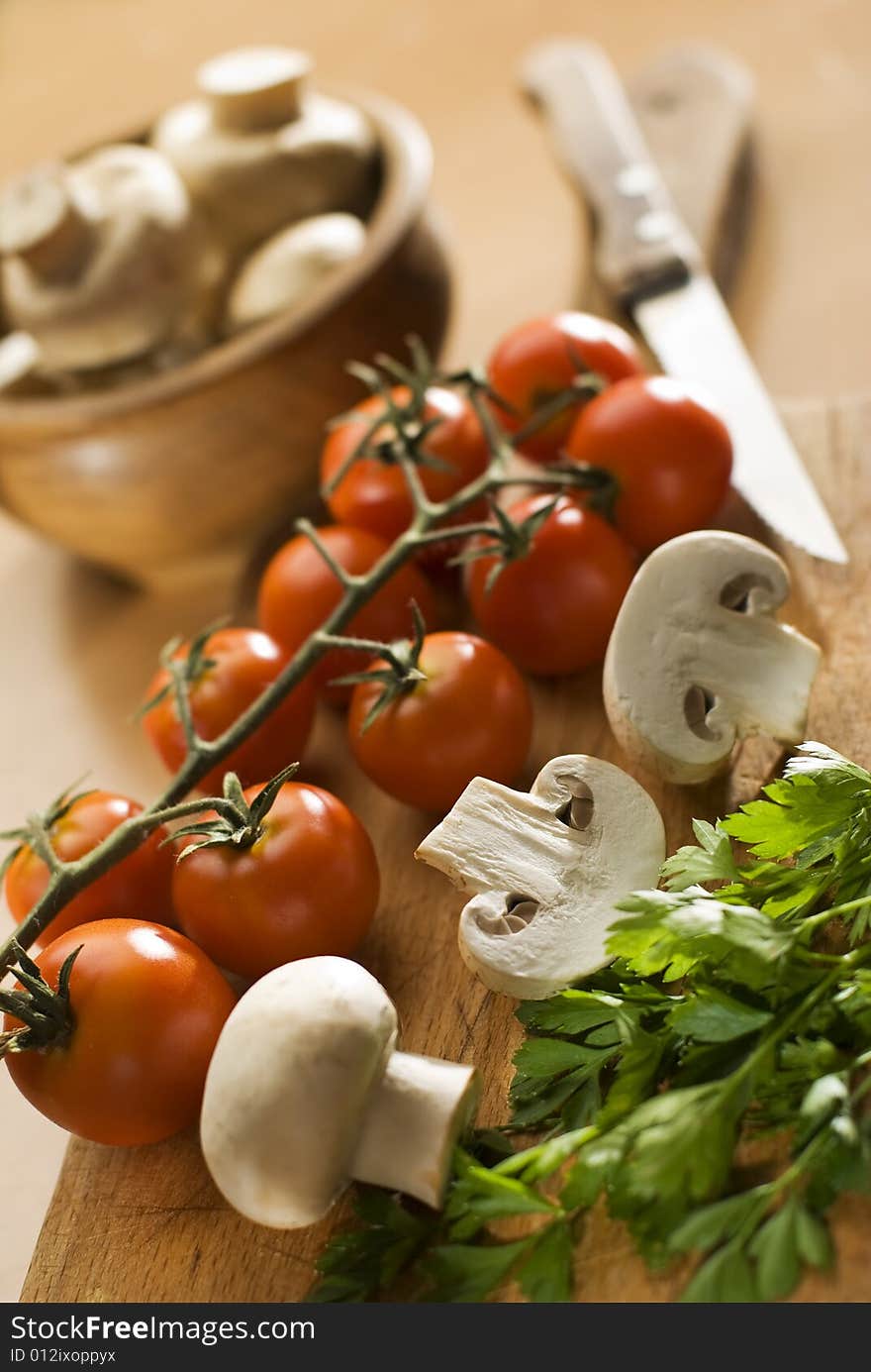 Fresh tomato and mushrooms on cutting board close up. Fresh tomato and mushrooms on cutting board close up