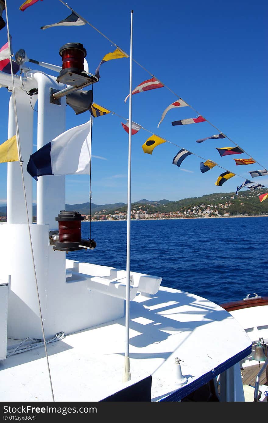 Coloured seafaring flags on a boat. These flags and their meaning costitutes the international code to communicate on sea. View of the city of Alassio in Liguria, Italy. Coloured seafaring flags on a boat. These flags and their meaning costitutes the international code to communicate on sea. View of the city of Alassio in Liguria, Italy.