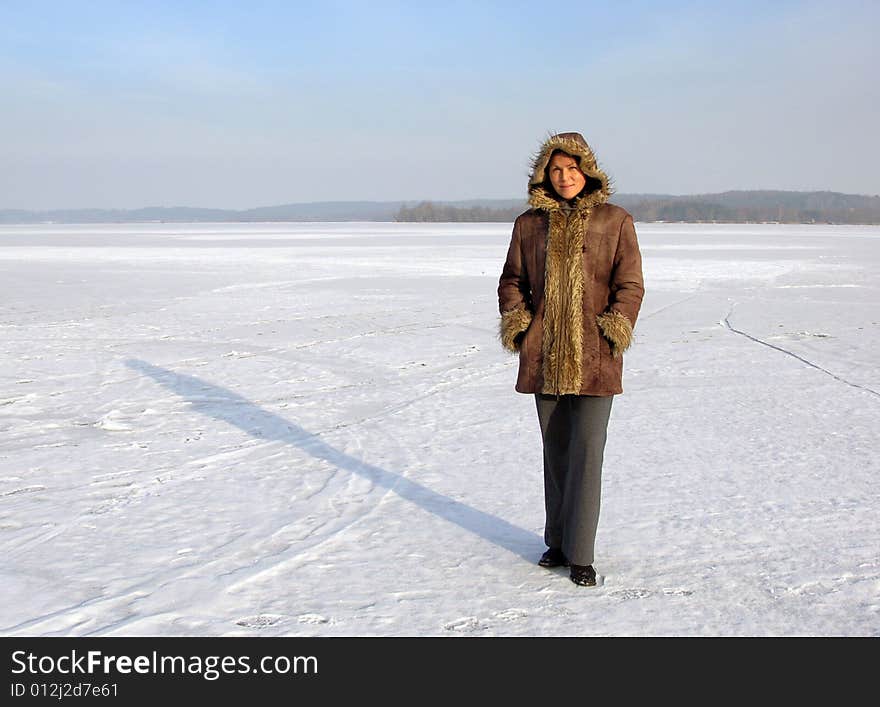 The girl standing on the vast frozen lake on a cold winter day in Lithuania. The girl standing on the vast frozen lake on a cold winter day in Lithuania.