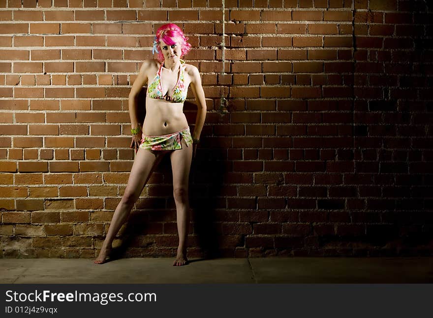 Pretty woman in a flowered bikini on a brick background. Pretty woman in a flowered bikini on a brick background