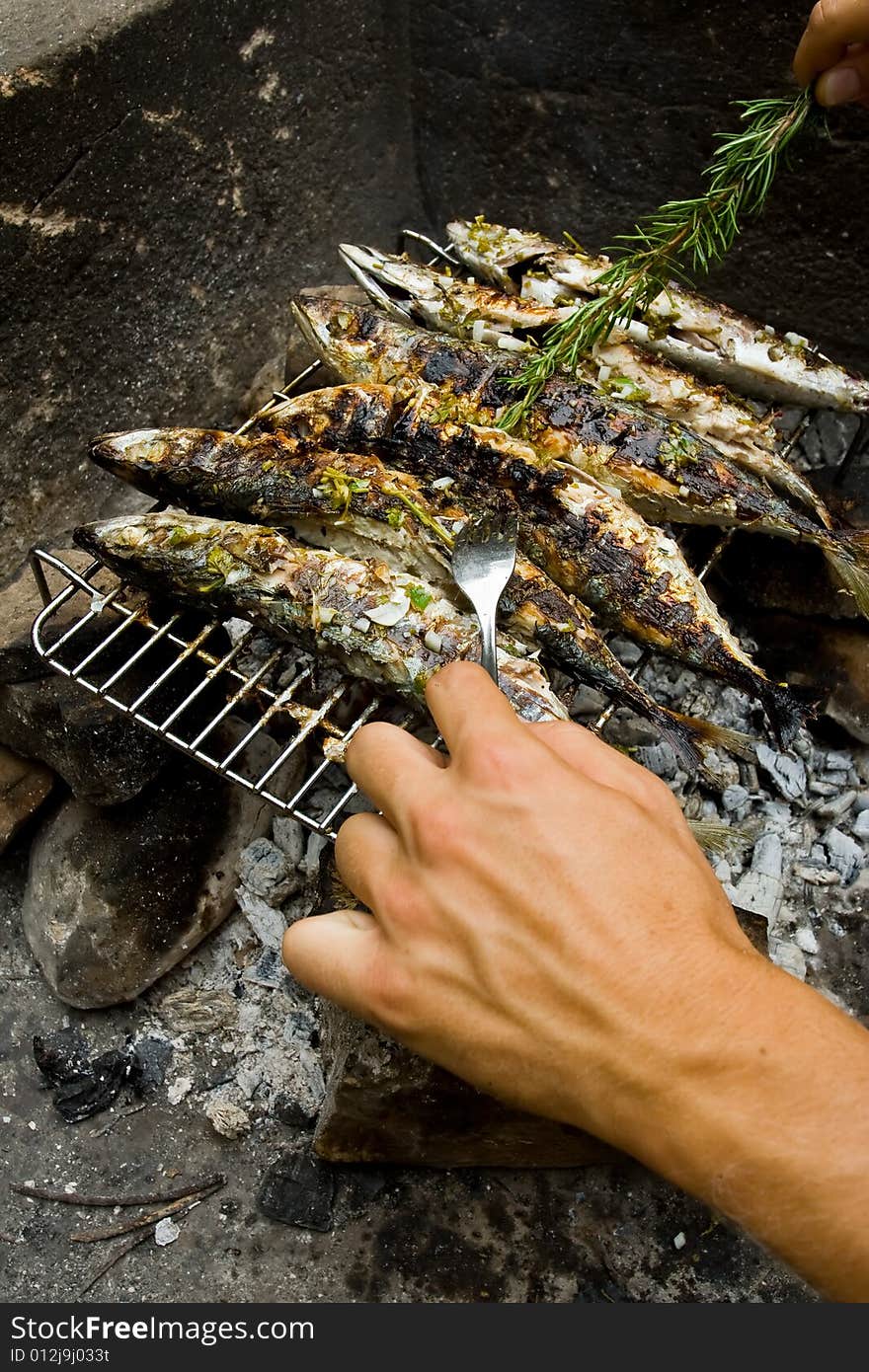 Man making grilled fishes with rosemary