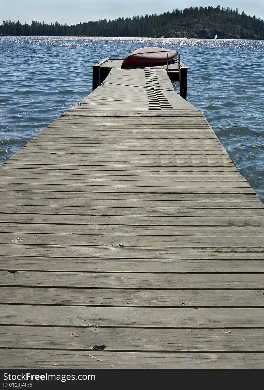 Old boat dock on a summer lake with a boat