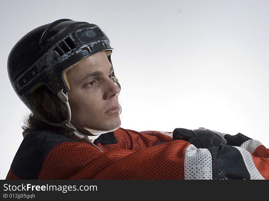 Seated hockey player looks off in the distance with a calm look on his face.  Horizontally framed photograph. Seated hockey player looks off in the distance with a calm look on his face.  Horizontally framed photograph