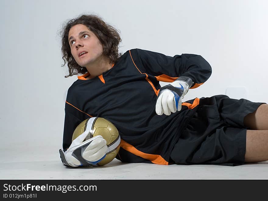 A man is dressed in a soccer uniform and posing in a studio.  He is holding a soccerball and looking away from the camera.  Horizontally framed shot. A man is dressed in a soccer uniform and posing in a studio.  He is holding a soccerball and looking away from the camera.  Horizontally framed shot.