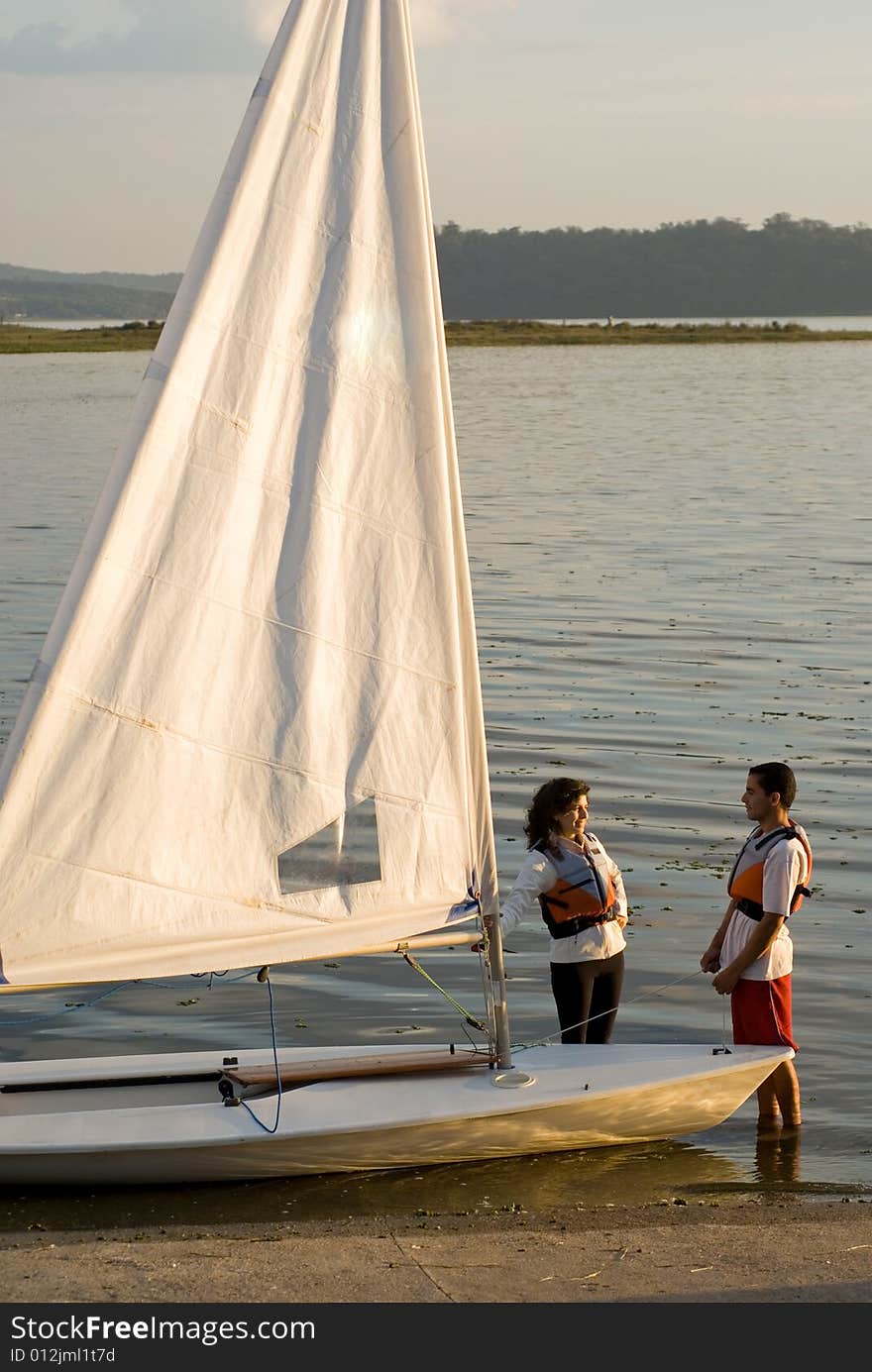 Couple Standing Next To Sailboat - Vertical