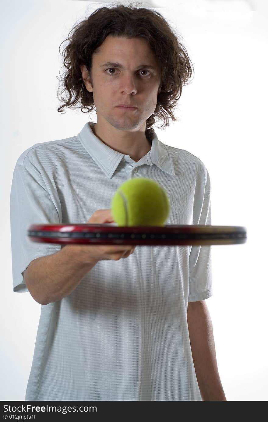 Man holding a tennis racket with a tennis ball and looking at the camera.  Vertically framed photo. Man holding a tennis racket with a tennis ball and looking at the camera.  Vertically framed photo.