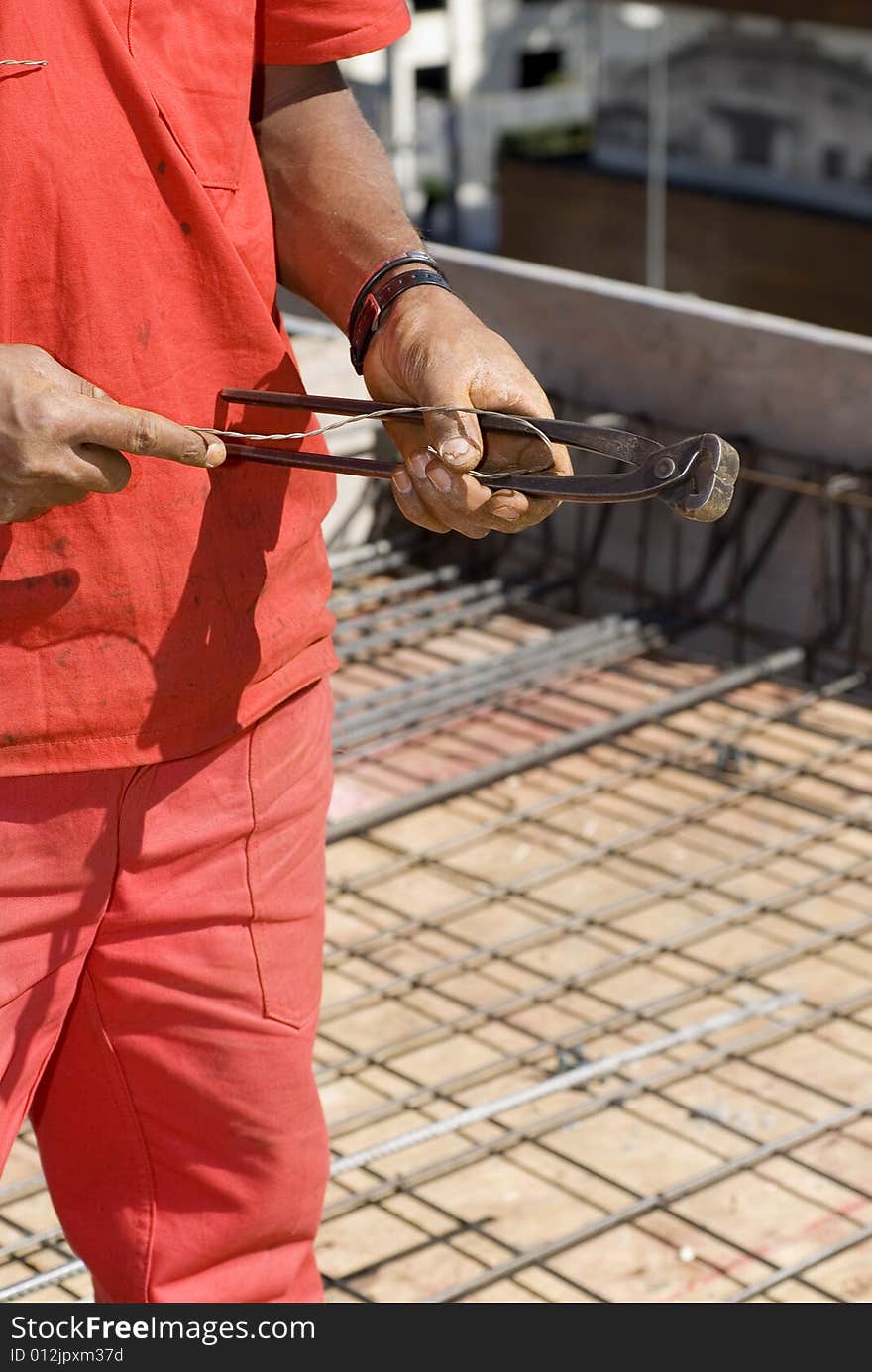 Construction worker holds cutting tool. He is standing amoung rebar and new construction. Vertically framed photo. Construction worker holds cutting tool. He is standing amoung rebar and new construction. Vertically framed photo.