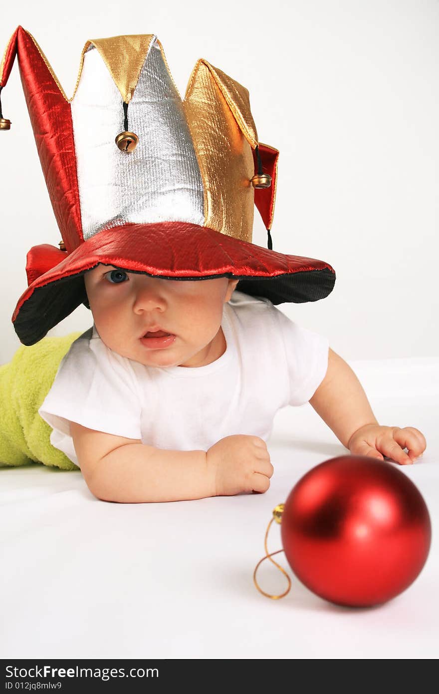 Small boy in the hat of jester plays with the red sphere