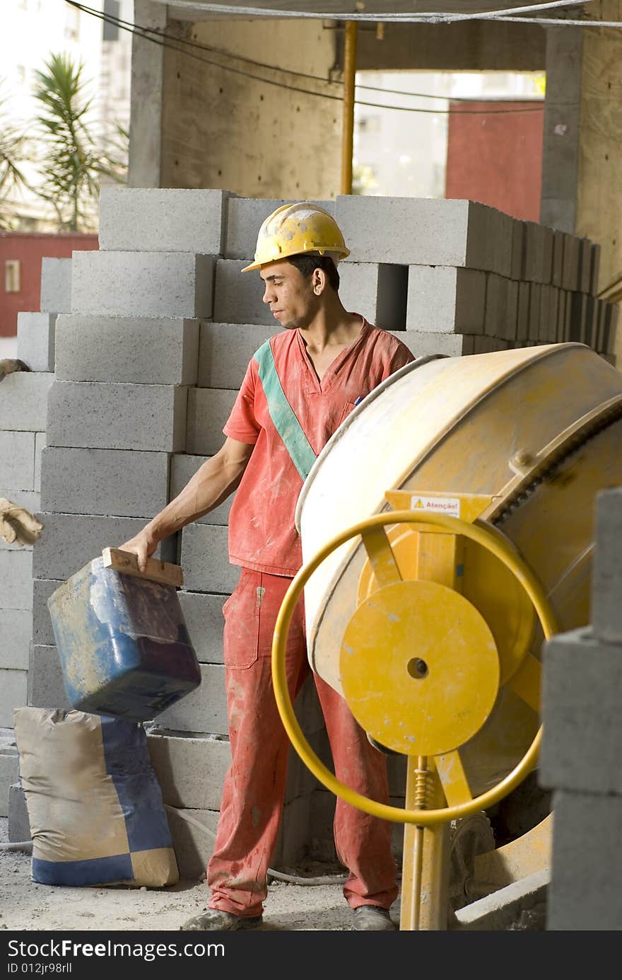 Worker Stands in Front of Cement Mixer - Vertical