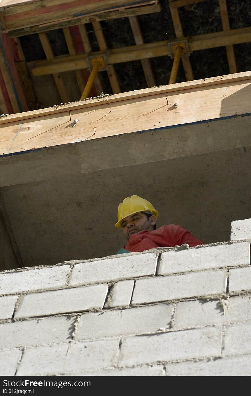 Worker Looks Over Cinder Block Wall - Vertical