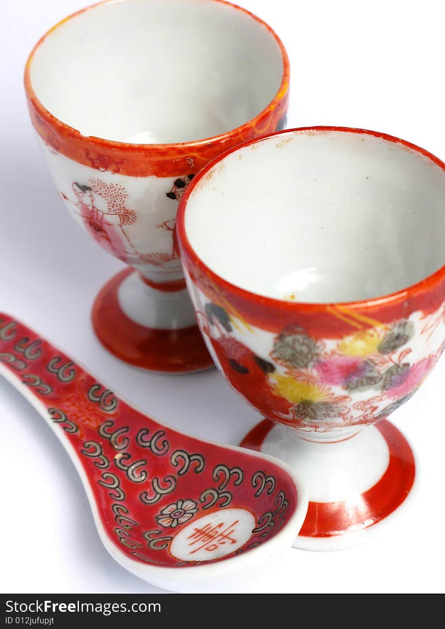 Two tea cups and spoon painted from China on a white background. Two tea cups and spoon painted from China on a white background