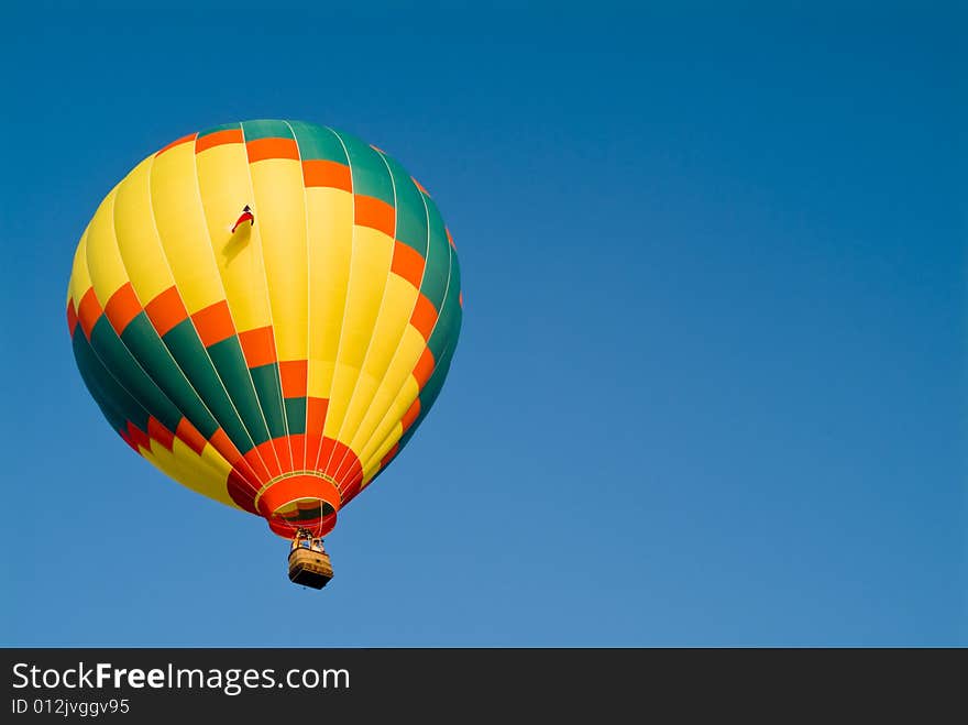 A colorful hot air balloon floating in a bright blue sky. A colorful hot air balloon floating in a bright blue sky.