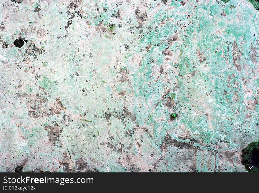 Concrete wall with cracked gray paint worn by weather.