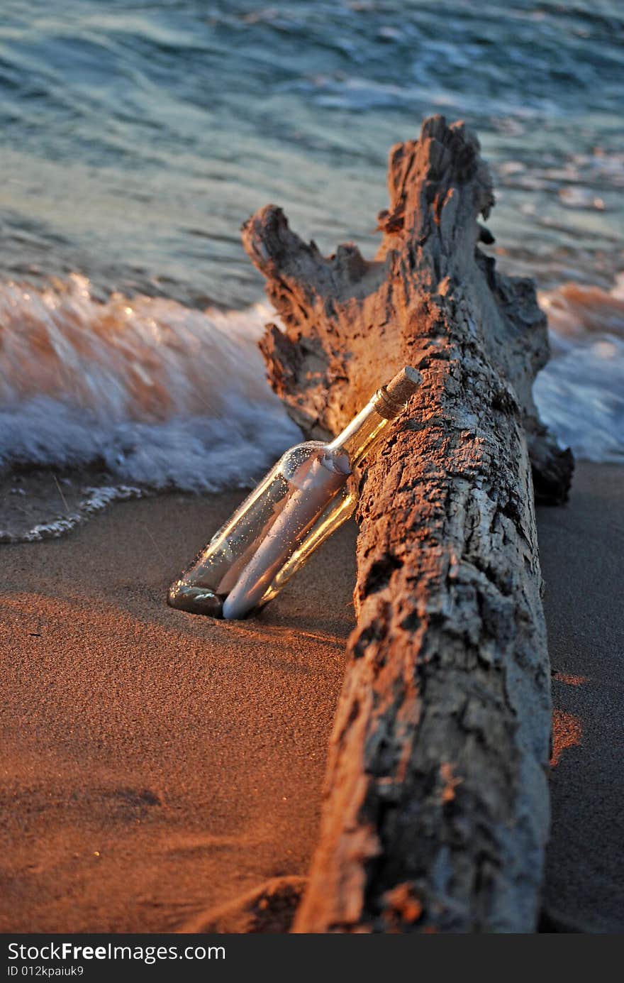 Message in a bottle propped up on a driftwood log. Message in a bottle propped up on a driftwood log.