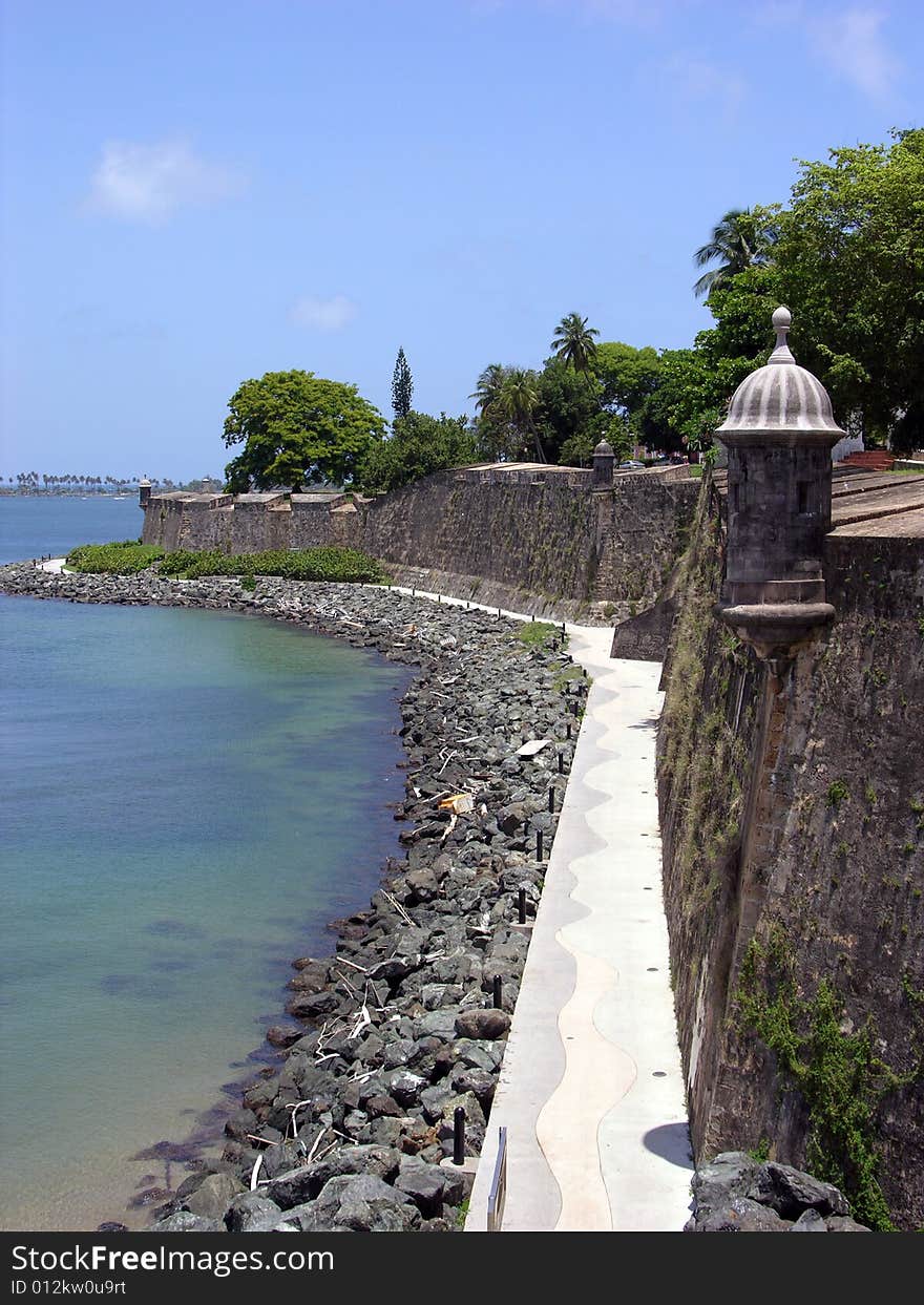 The view of the alley along the wall of historic San Felipe del Morro fort in the old town of San Juan, the capital of Puerto Rico. The view of the alley along the wall of historic San Felipe del Morro fort in the old town of San Juan, the capital of Puerto Rico.