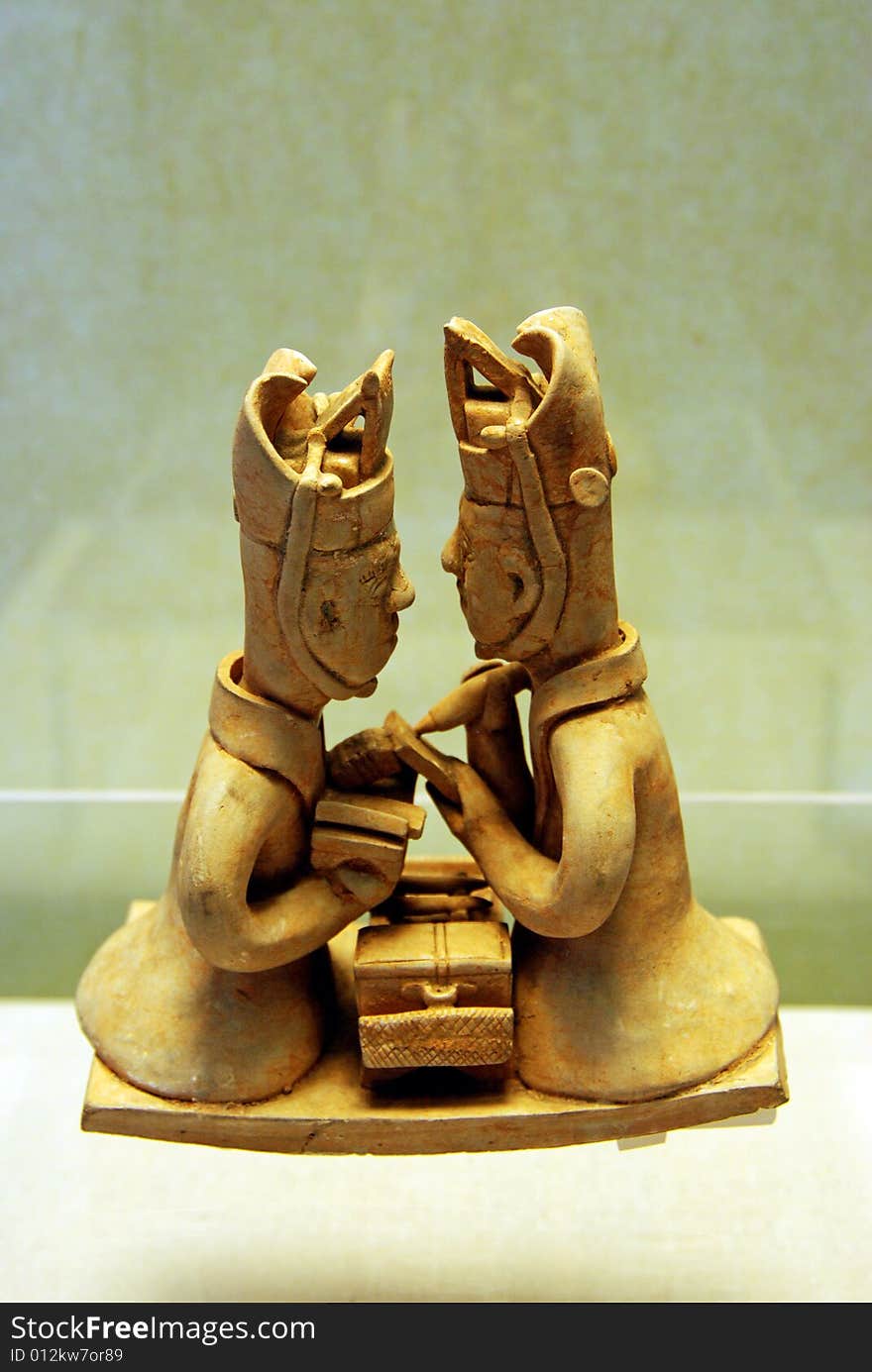 Pottery figures of two men studying together face to face