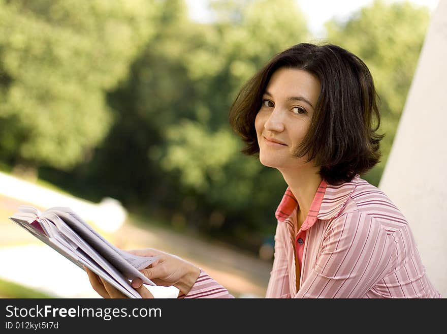 Portrait of pretty woman reading in park