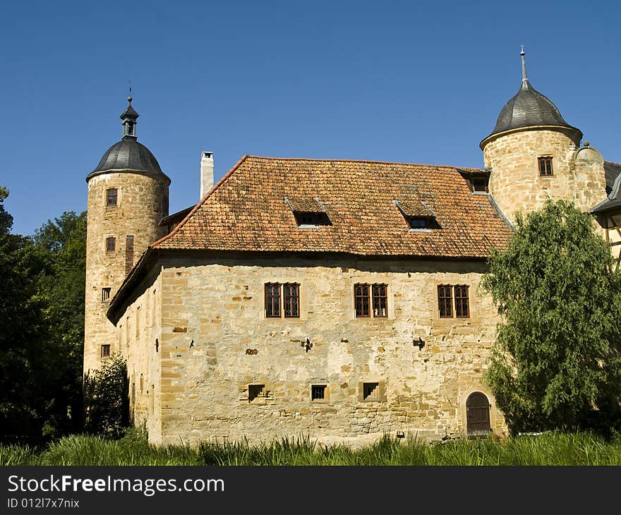 German castle with two towers and made from natural stone at the summertime