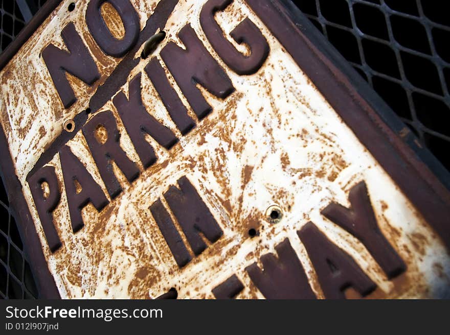 Street sign saying 'No Parking in Driveway' mounted on a metal grate of a gate.