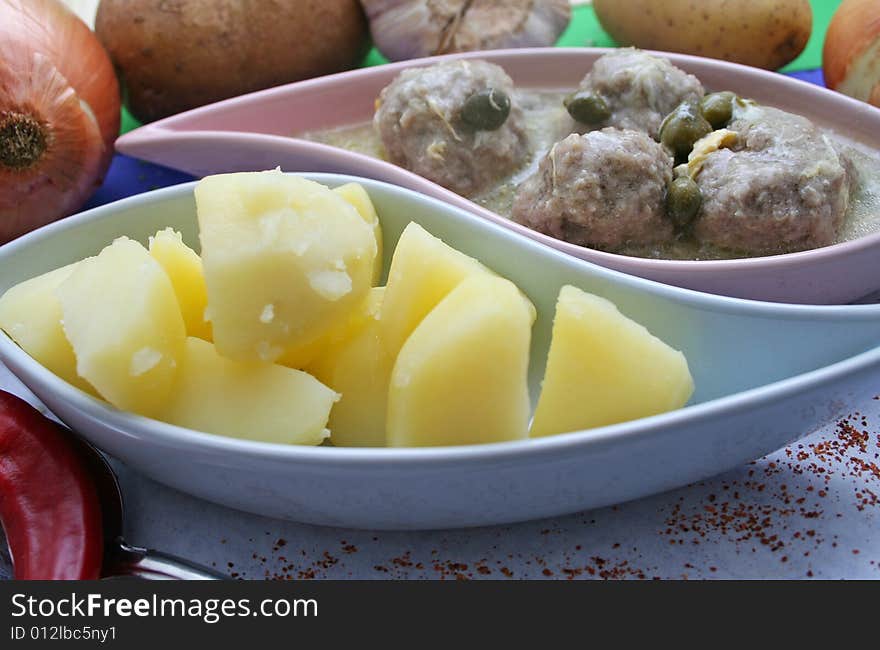 A meal with meat, capers and some potatoes