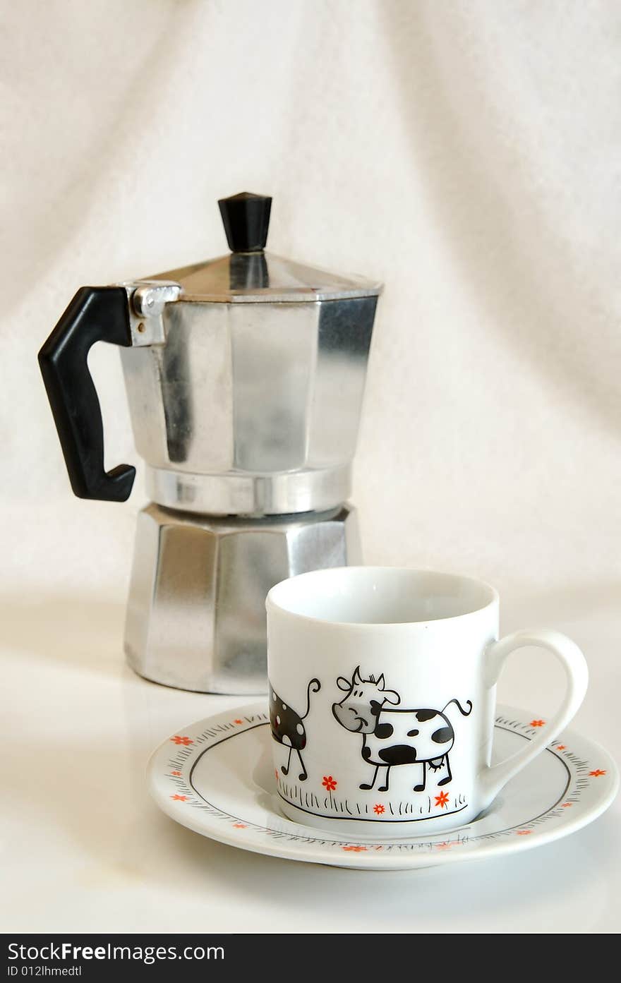 White cup with picture of cow against coffee-maker. White cup with picture of cow against coffee-maker