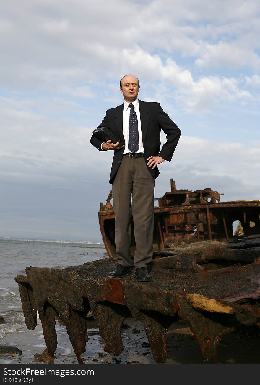 A businessman standing middle of a rusting ship looking out for a bright business future. A businessman standing middle of a rusting ship looking out for a bright business future.