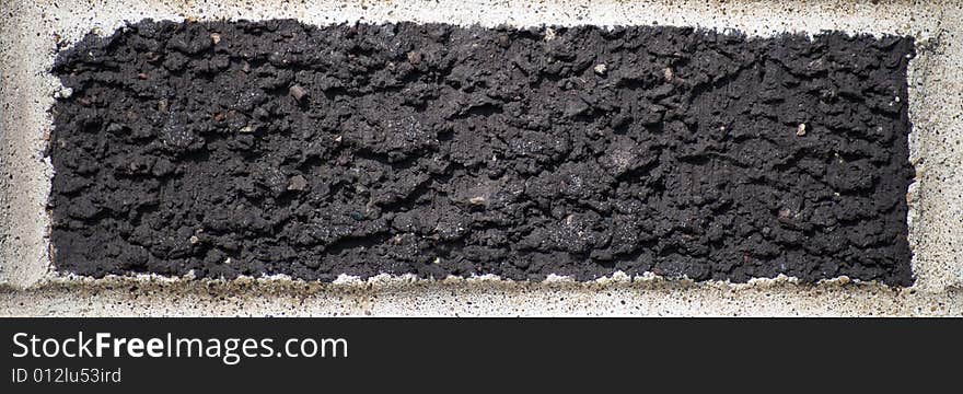 Single black brick surrounded by cement