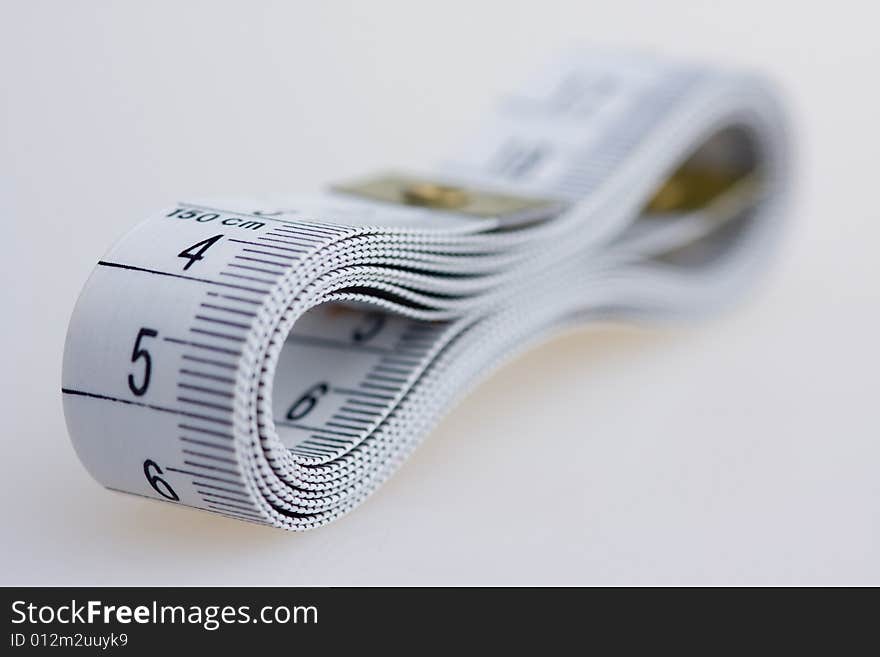 A white measuring tape on a white surface.