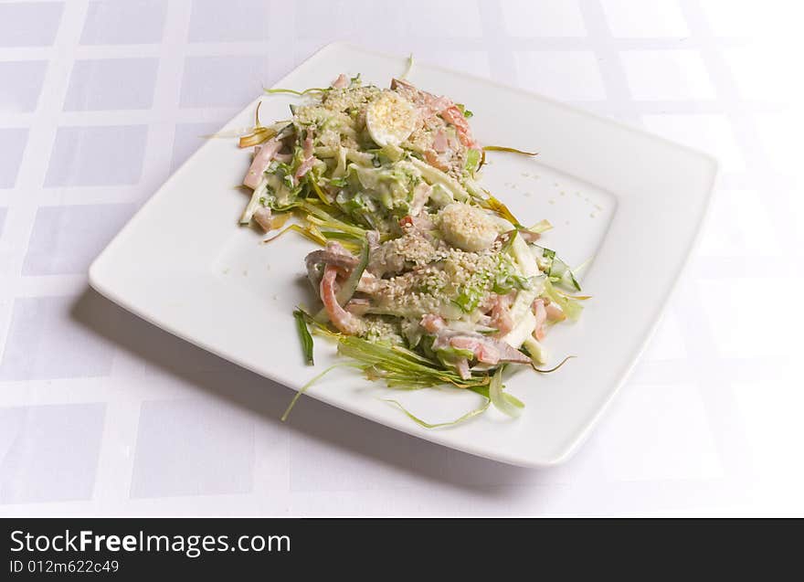 Salad with ham, eggs and herbs on white plate. Salad with ham, eggs and herbs on white plate