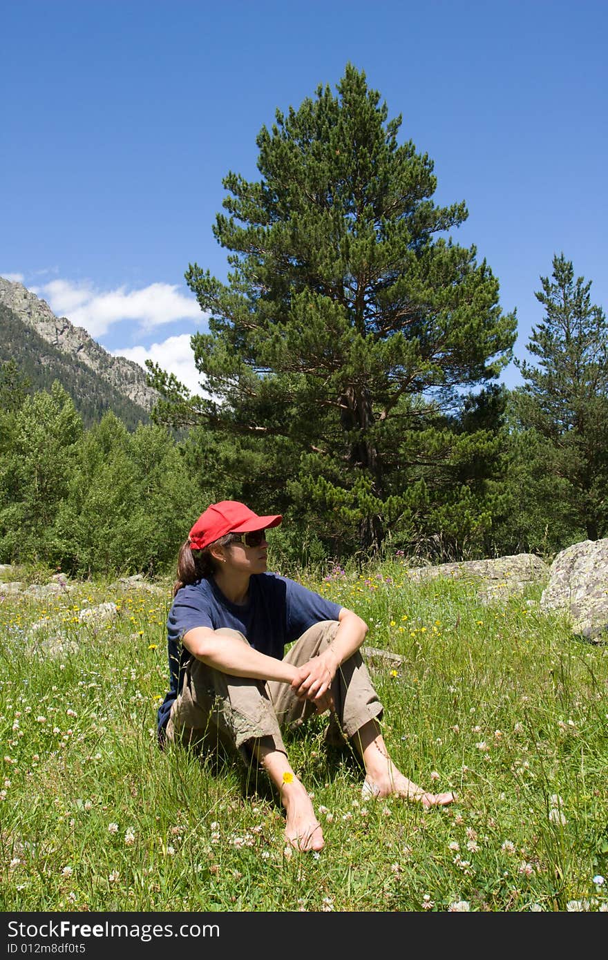 Tourist girl sitting on flowering meadow