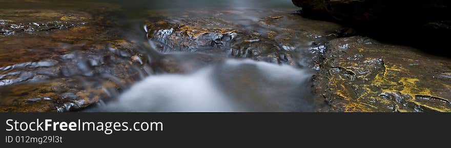 Pano stitch of rocks in a waterfall, with water creating misty effect. Pano stitch of rocks in a waterfall, with water creating misty effect.