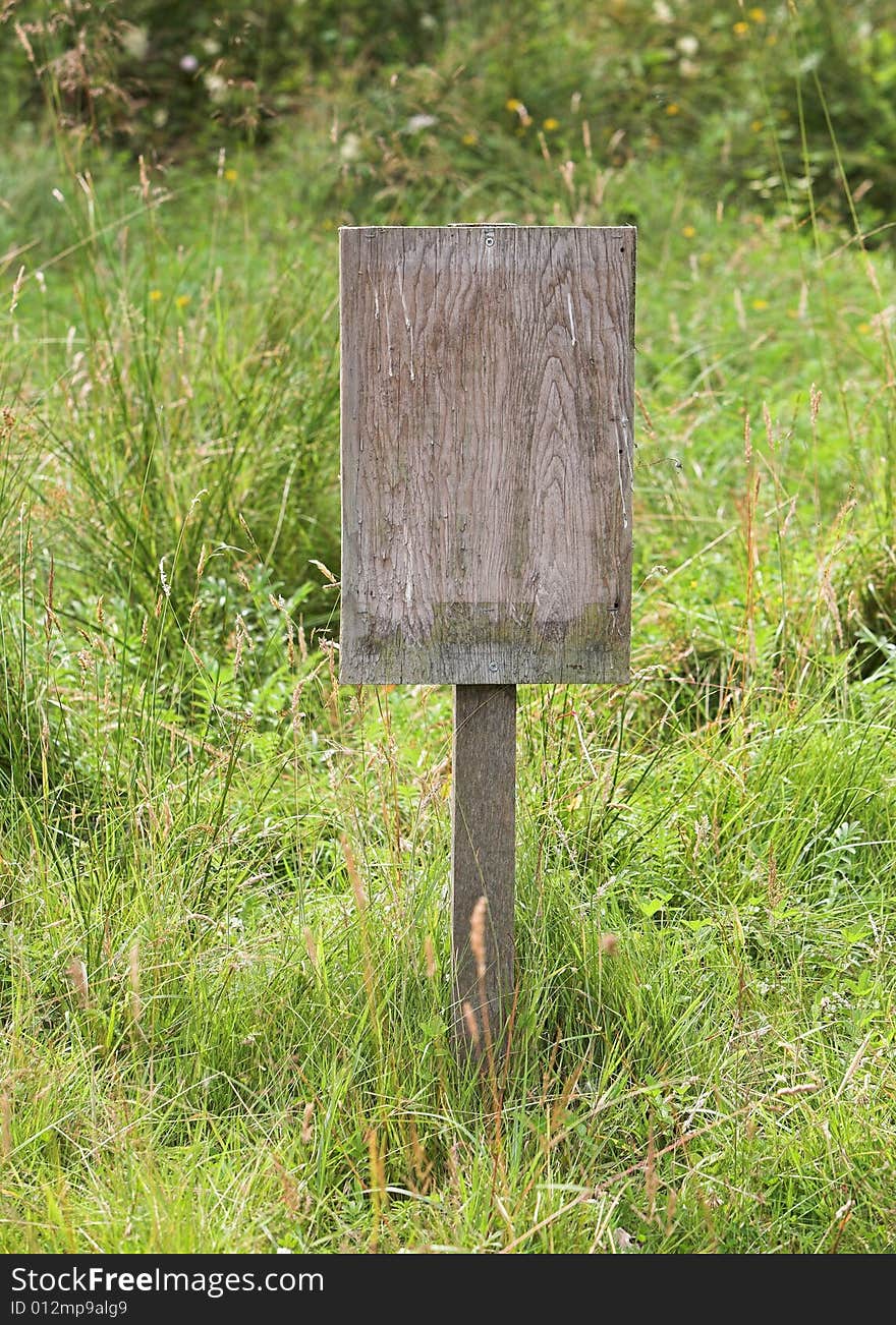 A blank wooden notice board in a meadow. A blank wooden notice board in a meadow.