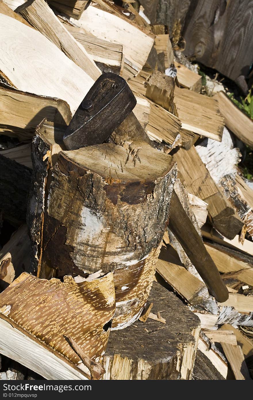 An old wood handled axe with chopped firewood background. An old wood handled axe with chopped firewood background.