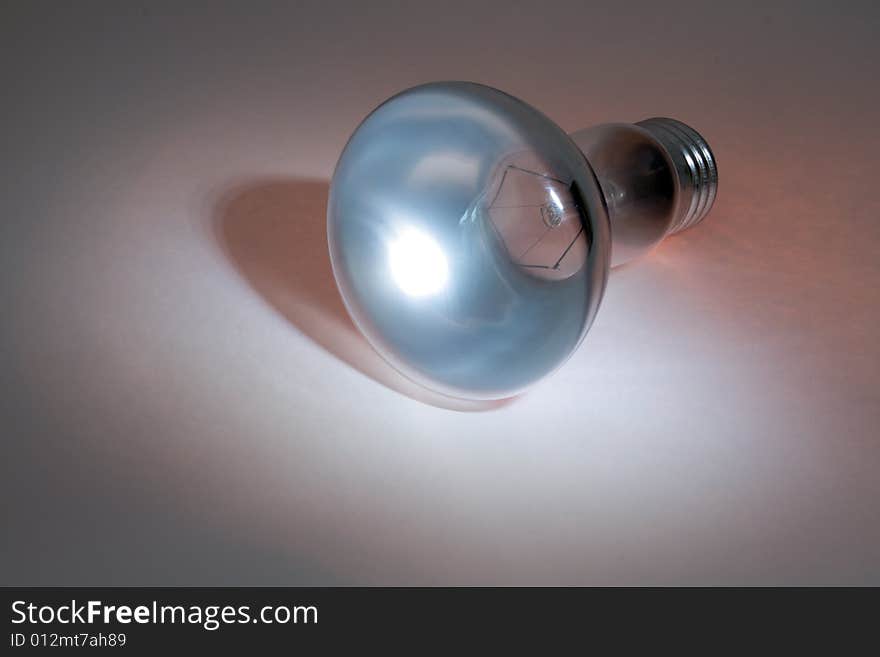 Glassy electric lamp lying on colored background. Glassy electric lamp lying on colored background