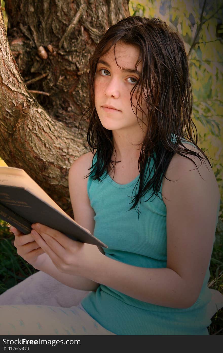 Teen girl reading a book under a tree. Teen girl reading a book under a tree