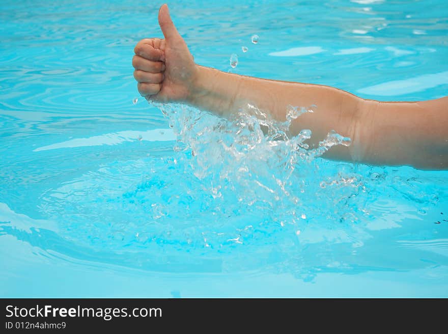 Hand gives gesture from blue water