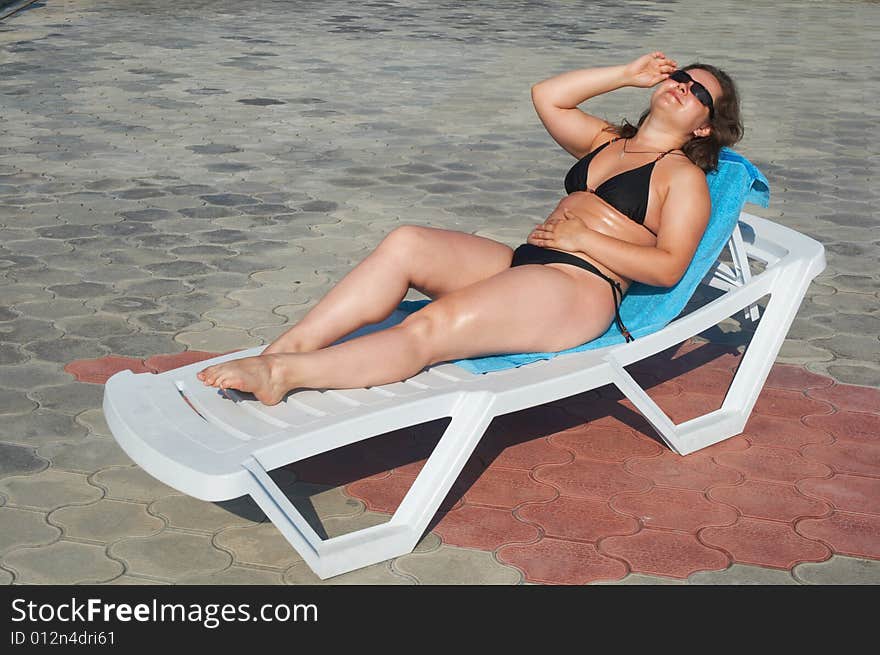 Girl in black bikini lying in chaise-longue. Girl in black bikini lying in chaise-longue