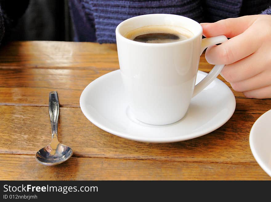 Female hand holding a cup of coffee in cafe