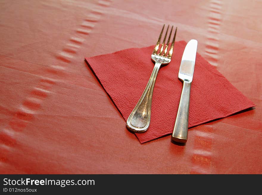 Fork and knife with red napkin on the table. Fork and knife with red napkin on the table