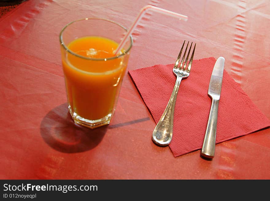 Dinnerware and glass of juice on red tablecloth in the restaurant. Dinnerware and glass of juice on red tablecloth in the restaurant