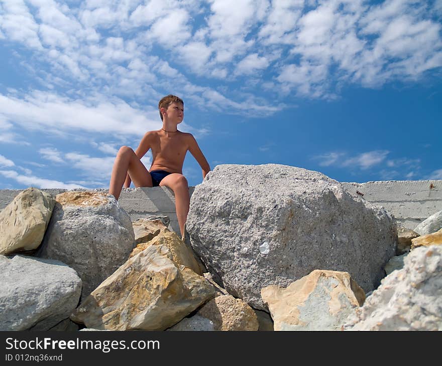 Child  ouydoor in sunny day sittng on big stones. Child  ouydoor in sunny day sittng on big stones