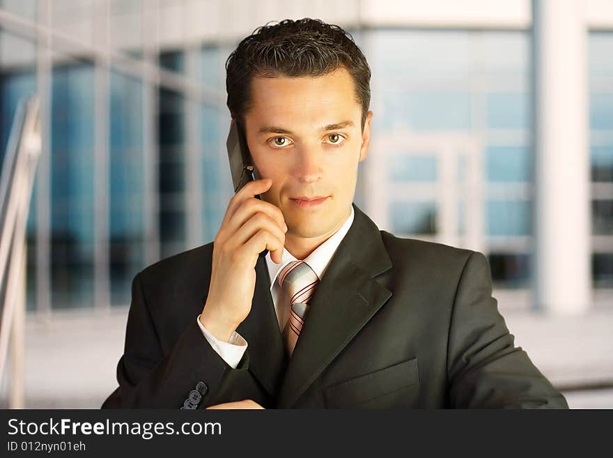 Close-up portrait. Businessman outside a modern building with phone. Close-up portrait. Businessman outside a modern building with phone.