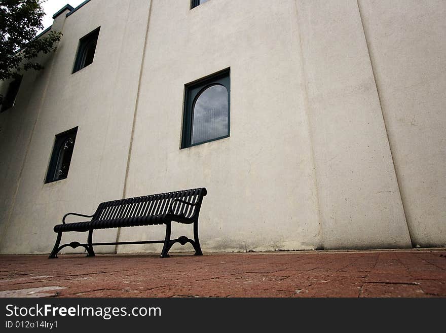 Metal bench against white wall of a building in downtown Plano, TX shot in July, 2008. Metal bench against white wall of a building in downtown Plano, TX shot in July, 2008.