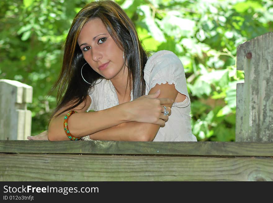 A young lady leans on the wooden rail of a bridge. A young lady leans on the wooden rail of a bridge