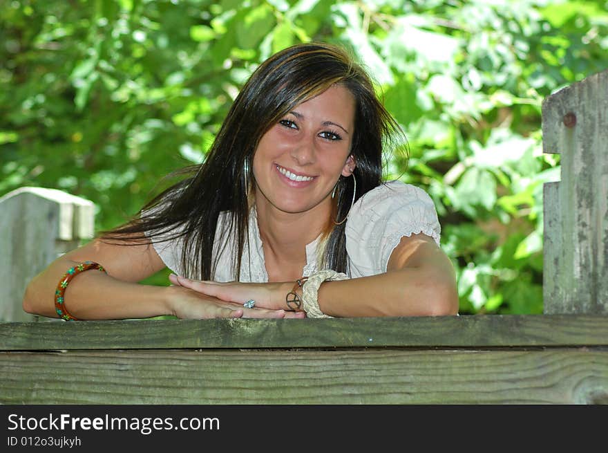 A young lady leans on the wooden rail of a bridge. A young lady leans on the wooden rail of a bridge