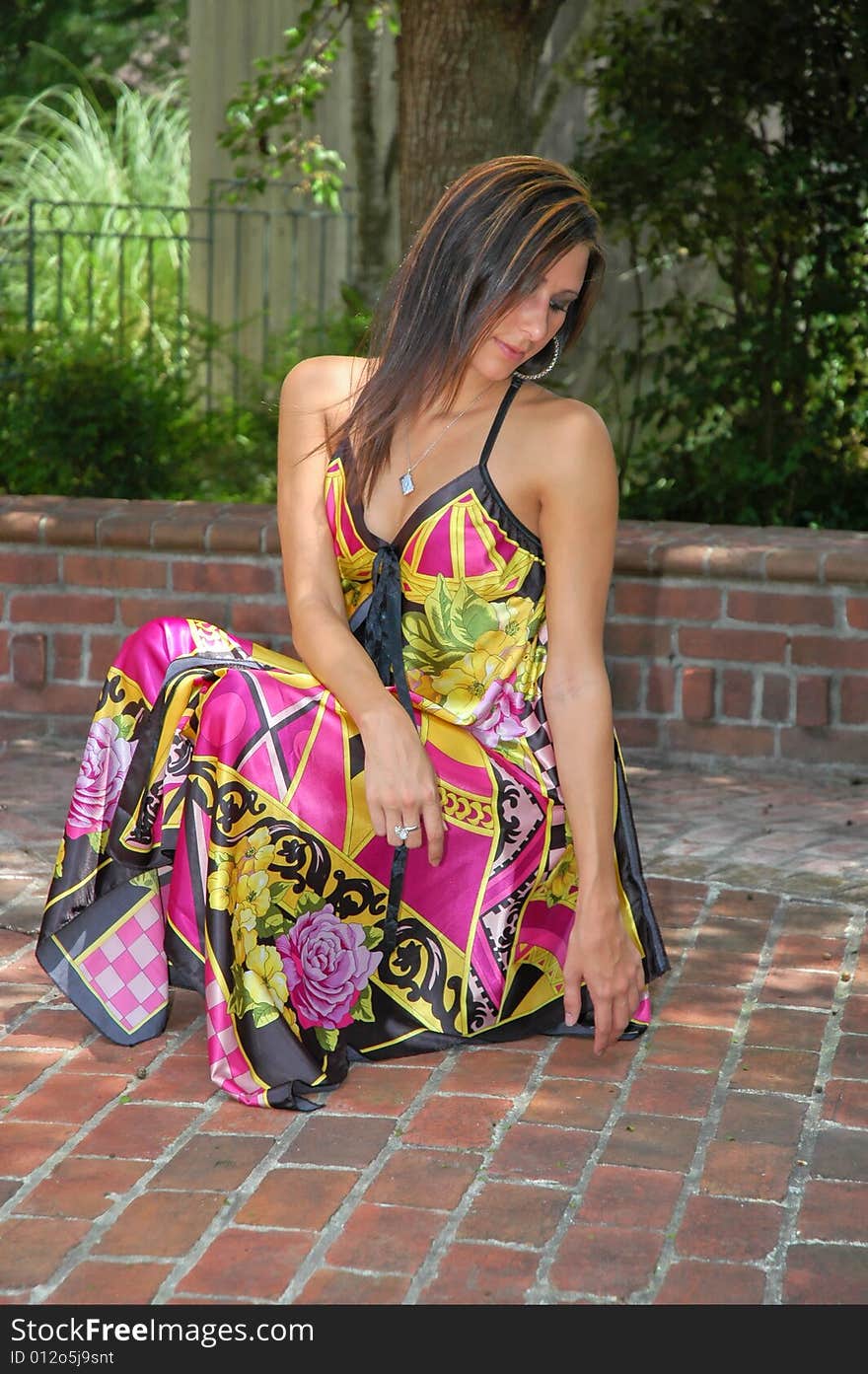 A young lady poses in a colorful flowing dress on a brick platform. A young lady poses in a colorful flowing dress on a brick platform.