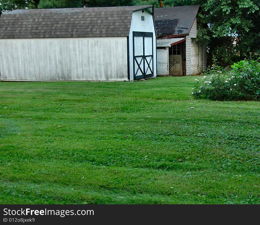 Evening warm light shot of old rural barn with evening green lit foreground of deep green grass. Evening warm light shot of old rural barn with evening green lit foreground of deep green grass