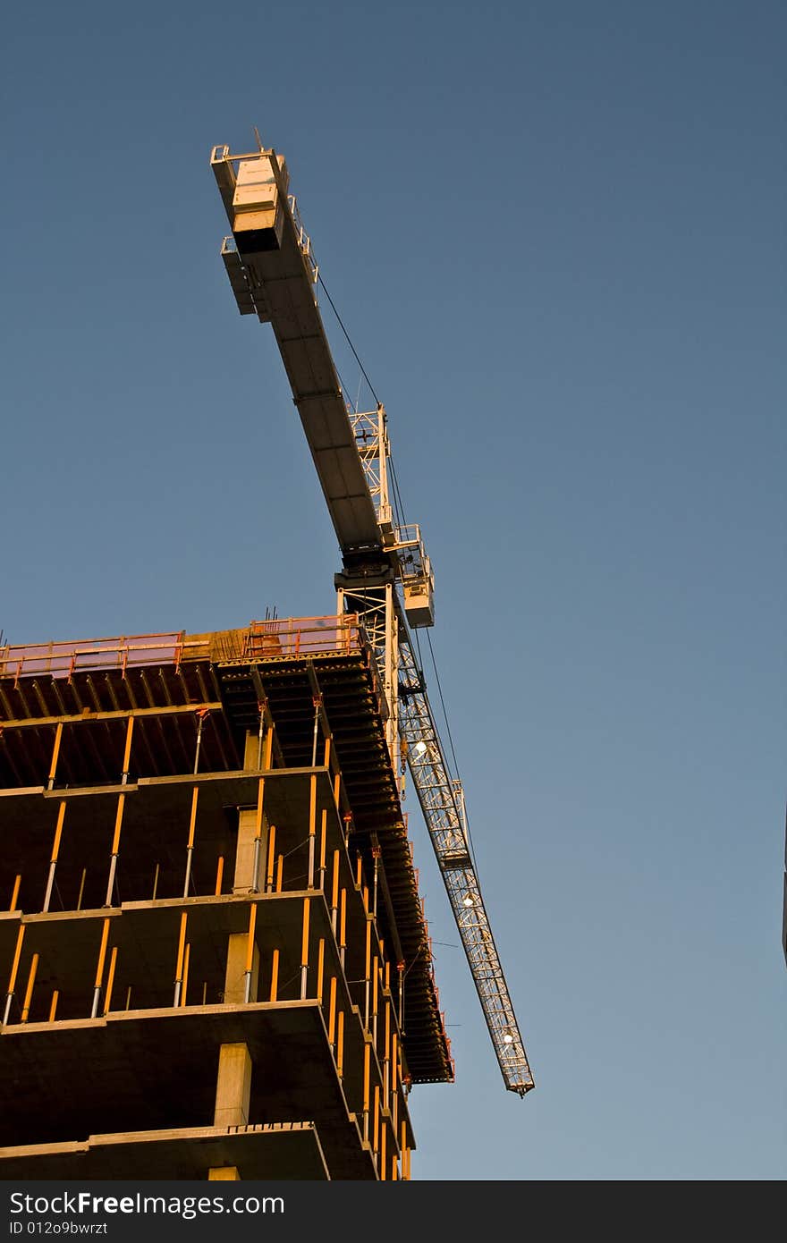 A very large tall crane is used to help lift materials up to the top of a very tall building. A very large tall crane is used to help lift materials up to the top of a very tall building.