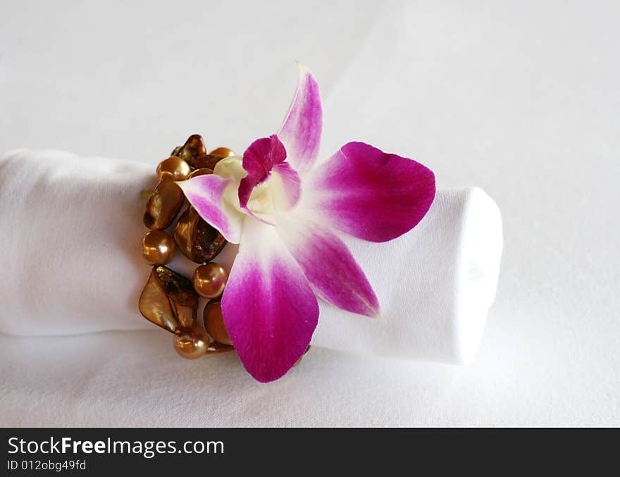 White napkin decorated with an orchid and precious stones. White napkin decorated with an orchid and precious stones.